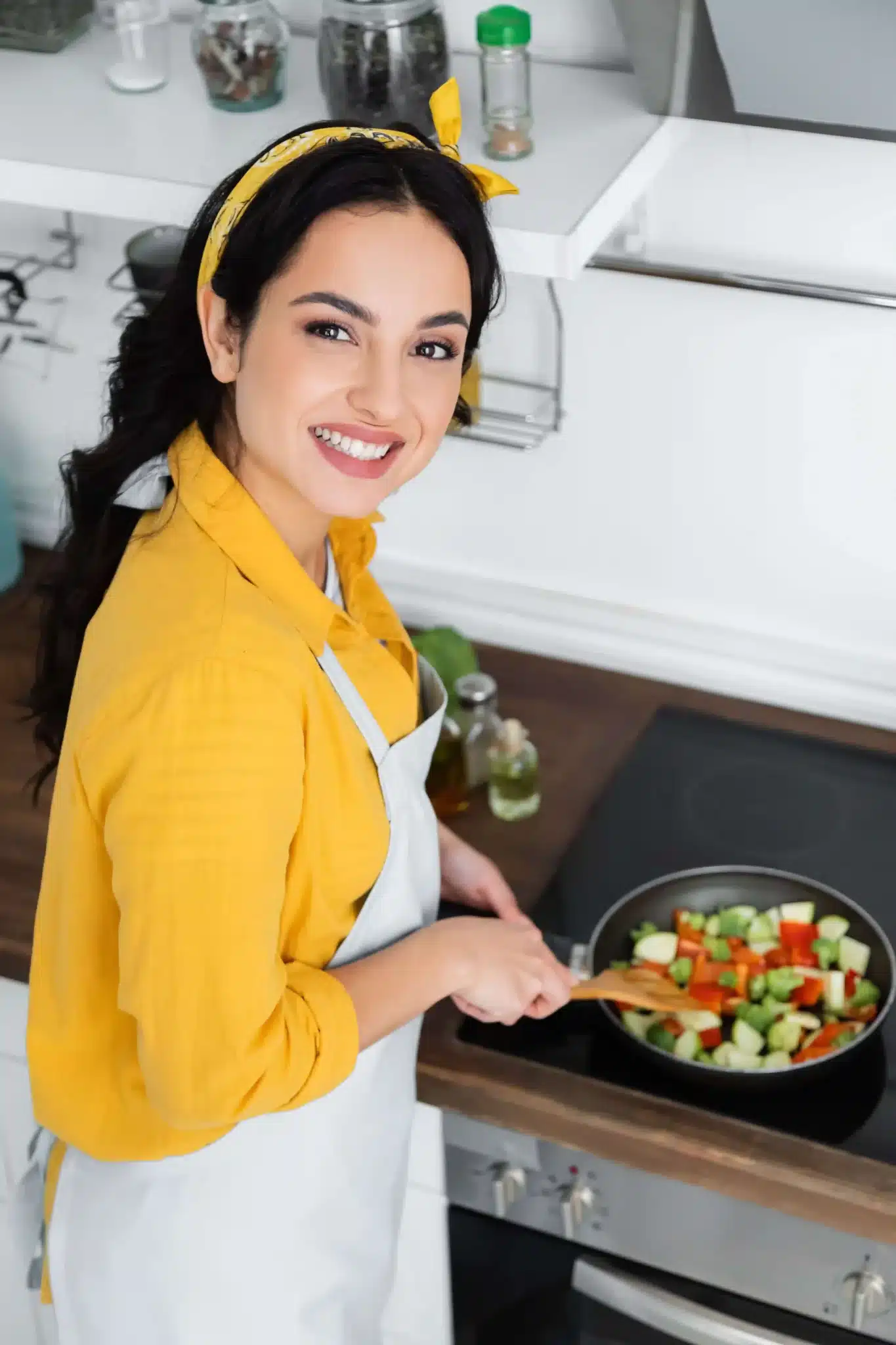 Meet Maya Sterling – Real-Life Recipes from a New York Kitchen Chef Maya Sterling smiling in a cozy kitchen, holding a wooden spoon near a stove with fresh ingredients on the counter.
